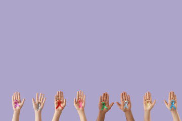 Many hands with different ribbons on lilac background. Cancer awareness concept