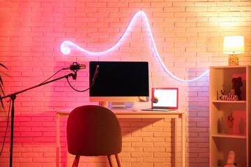 Interior of recording studio with workplace, microphone and glowing neon lamp