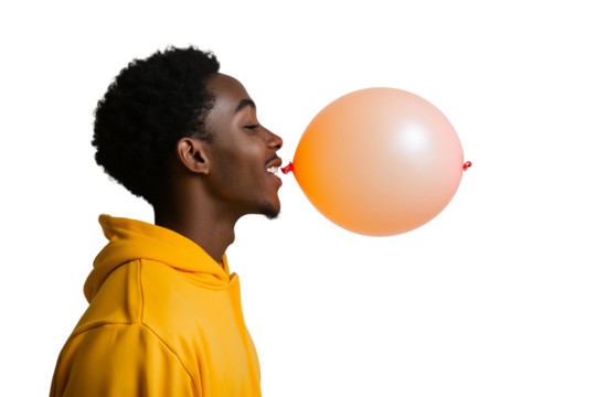 a front view image of a 18 year old african american male leaning in and blowing up a ballon, head turned in profile to one side, happy, yellow orange hooded sweatshirt, on a white background