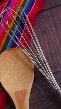 Utensilios de cocina, con mantel mexicano sobre mesa de madera, en vertical