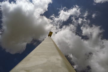 Low-angle view of a street lamp against a backdrop of dynamic clouds and blue sky, representing...