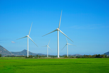 Windmill for electric power production. Wind turbines generating electricity on rice field at Phan...