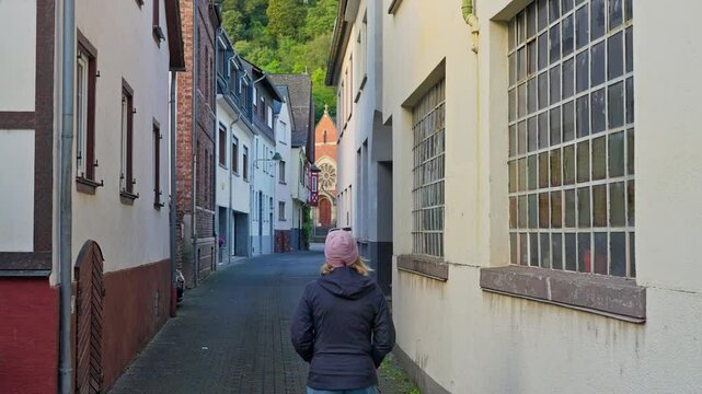Following behind woman walking on small narrow street in the medieval town of Oberwesel, Rhine Valley, Germany