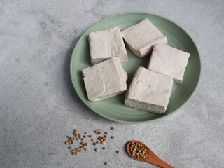 Tahu Putih or Tofu, one of raw ingredient food made from fermented soybean extract. Served in green plate with grey background. selective focus