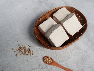 Tahu Putih or Tofu, one of raw ingredient food made from fermented soybean extract. served on wicker bamboo plate Isolated on grey background