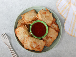 Tempe Kemul or Mendoan or fried tempeh with flour on a plate. Indonesian traditional snack, from fried tempeh with flour. Served with cayenne pepper. Street food snacks. gorengan