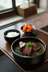 beef stew with rice and vegetables in black bowl on wooden table