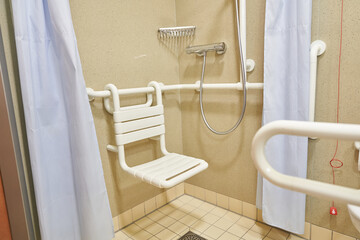 A shower room with a plastic chair in a hospital, designed for the disabled and people with limited mobility, with tiled floors and walls. High quality photo