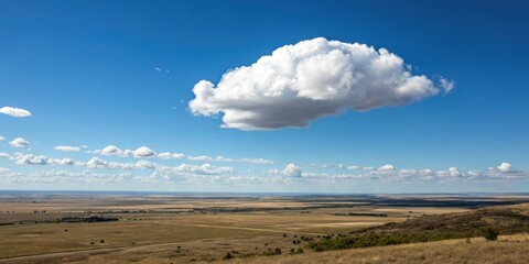 A lone white cloud floats serenely across the clear blue sky against a backdrop of endless plains and vast open spaces, floating, white cloud