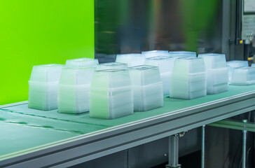 stack of polypropylene food containers on conveyor belt of automatic plastic injection molding...