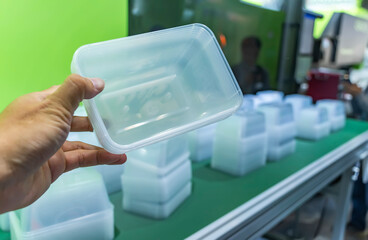hand with polypropylene food containers on conveyor belt of automatic plastic injection molding machine,automated technology concept