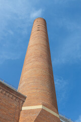 Full frame low angle view of a late 19th century industrial brick chimney, in sunlight with blue sky