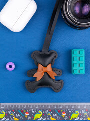 Close up of funny black leather bear keychain with brown bow on blue background