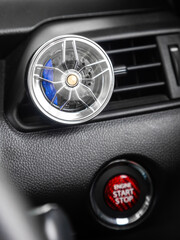 Close up of cast disc shaped air freshener on car dashboard vent