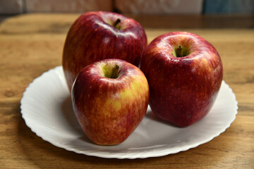Plate with apples and autumn leaves on wooden table