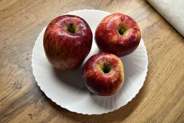 Plate with apples and autumn leaves on wooden table