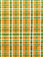 Obraz premium Colorful plaid fabric with a vibrant pattern showcasing green and orange hues ideal for various textile projects