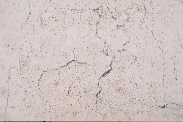 Texture of natural white stone with brown dots and cracks