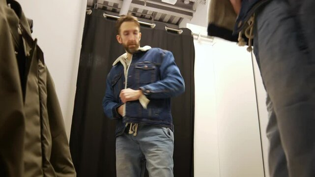 A man trying on a fleece lined denim jacket in a fitting room