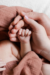 A vertical close-up of father's and mother's hands holding and revealing their newborn baby's...