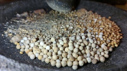 the process of grinding kitchen spices using traditional tools, namely a stone grinder