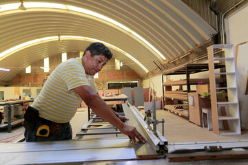 Fototapeta premium Carpenter cuts a board on the power saw