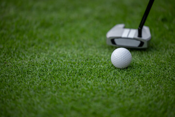 Putter and golf ball on green grass, Golf putter putting golf ball to the hole.