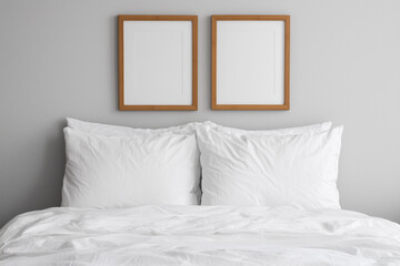 Minimalist bedroom with a neatly made white bed, fluffy pillows, and two wooden picture frames on a gray wall, modern and cozy interior design