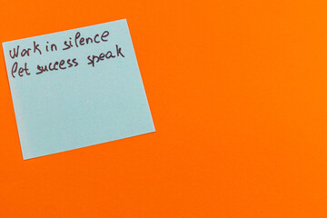 Motivational message on a note against a bright orange background
