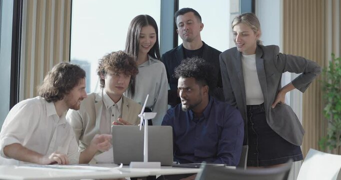 A diverse startup team develop, collaborates on a powerful, lightweight, portable wind turbine prototype, aligning with potential user demand and renewable energy needs to secure investor funding.
