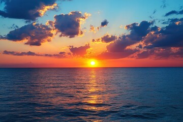 Obraz premium Serene ocean sunset with vibrant colors and dramatic clouds reflecting on the tranquil water surface creating a peaceful atmosphere