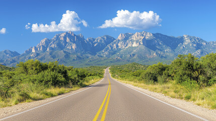 scenic road leads through lush greenery towards majestic mountains under bright blue sky
