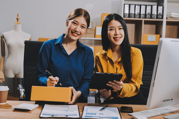 Asian SME business women use laptop computer checking customer order online shipping boxes at home....