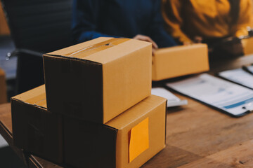 Asian SME business women use laptop computer checking customer order online shipping boxes at home....