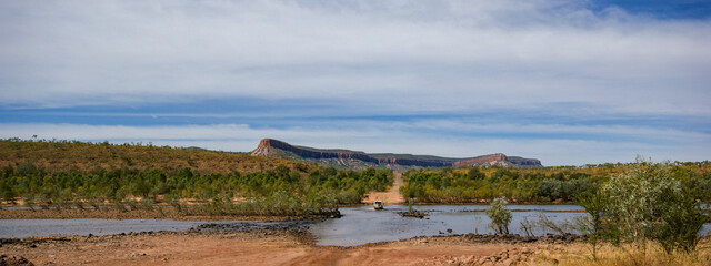 Vehicle crossing the Pentecost river on Gibb river road, Cockburn Range in background, Kimberleys, Western Australia