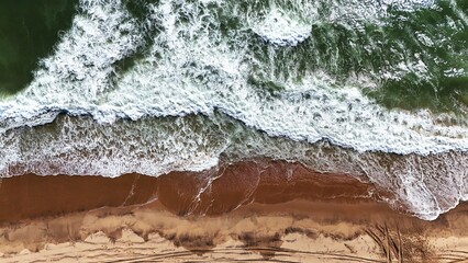 Aerial View of Waves Crashing on the Namibian Coastline with Car Tracks on the Sand
