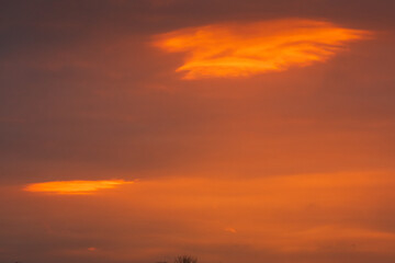 Spectacular British Dawn Sky with Burning Orange Cloud Formation. Natural abstract sunrise background captured in the UK with glowing tangerine clouds and atmospheric drama
