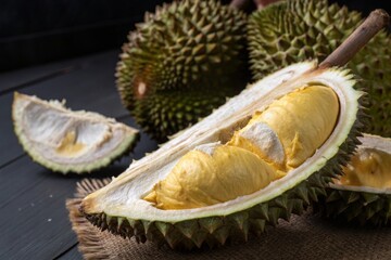 Cutting open durian tropical market food photography dark wood background close-up view golden creamy delight