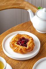 bun with cherry frosting on a wooden table