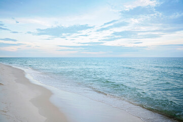 Serene beach with gentle waves, soft sand, and a pastel sky