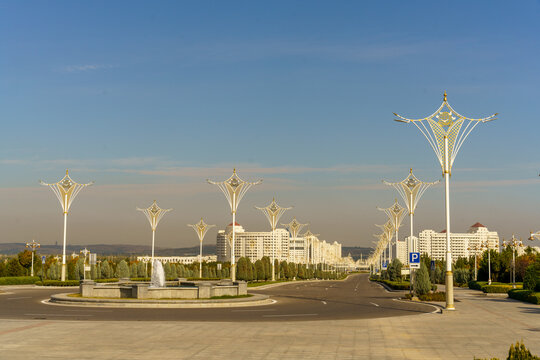 A city street with a fountain in the center and a lot of street lights