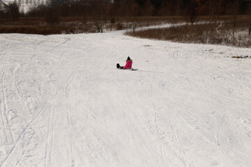 Behind young girl sledding down steep snow covered hill