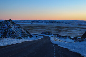 Sun setting over a winding road in the Badlands