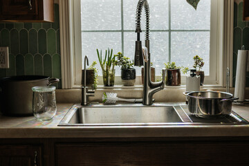 View of kitchen sink in front of window with pots and plants
