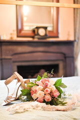 Bridal bouquet, glitter heels, and accessories on a bed near a f