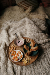 Cozy breakfast tray with yogurt, bread, and fruit on a soft blanket