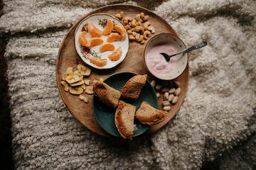 Cozy breakfast tray with yogurt, bread, and fruit on a soft blanket