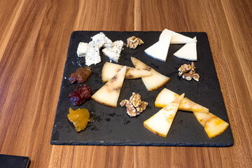 A black tray with a variety of cheeses and nuts on it
