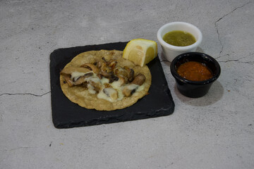 A plate of food with a tortilla, cheese, and mushrooms