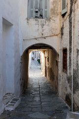 Narrow alley with tunnel and with whitewashed walls and stone pavement leading to a courtyard in the Greek Islands, Greece